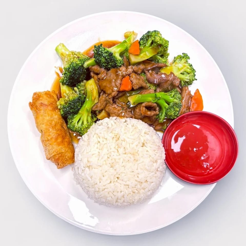 Bamboo House's beef and broccoli with white rice, an egg roll, and red sauce on a white plate.