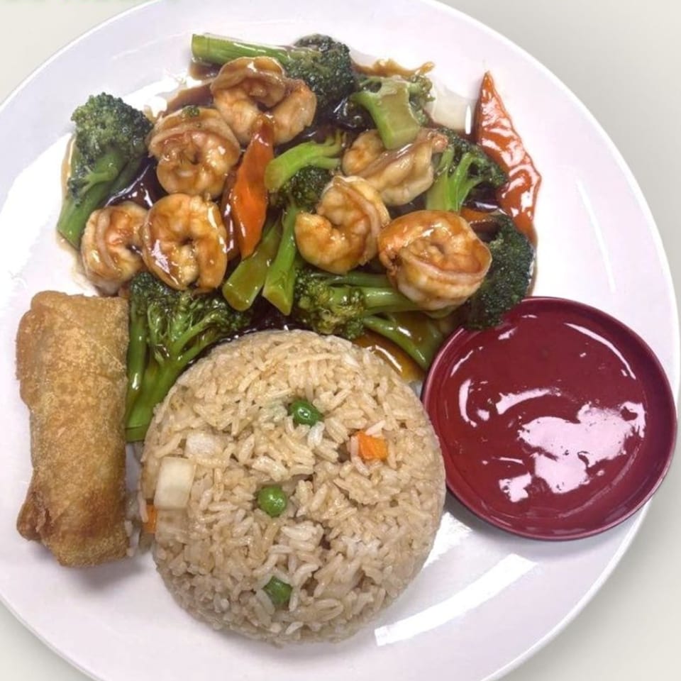 Shrimp and broccoli stir-fry with fried rice, an egg roll, and a side of red sauce.