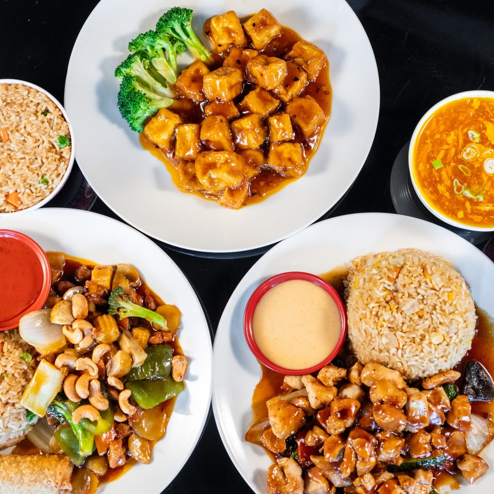 Three plates of Chinese food, including General Tso's tofu, cashew chicken, and chicken with vegetables.